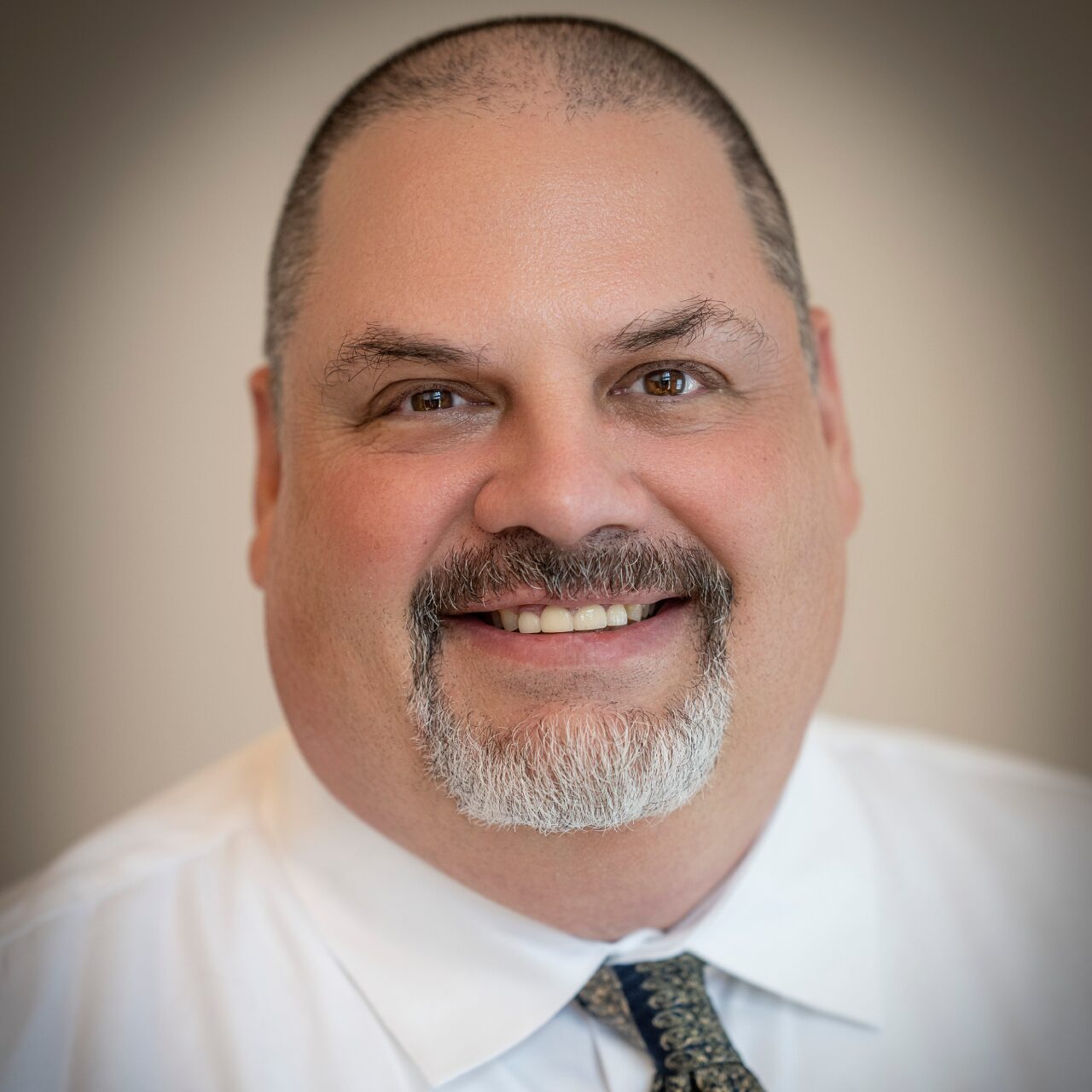 Smiling middle-aged man with a beard and tie.