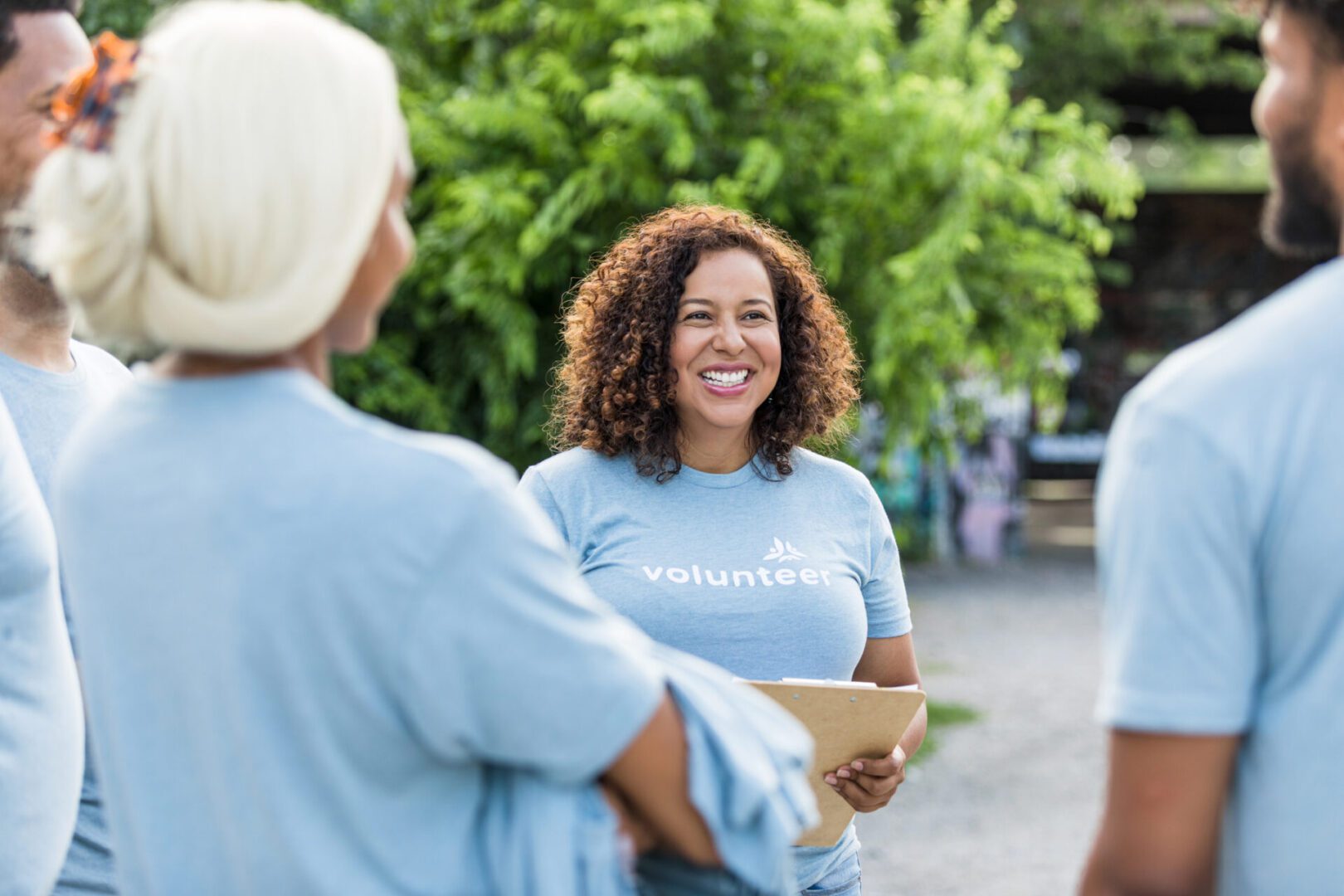 Smiling volunteers in blue shirts outdoors.